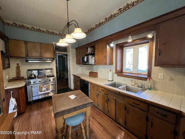 kitchen with tile counters, appliances with stainless steel finishes, dark wood finished floors, and a sink