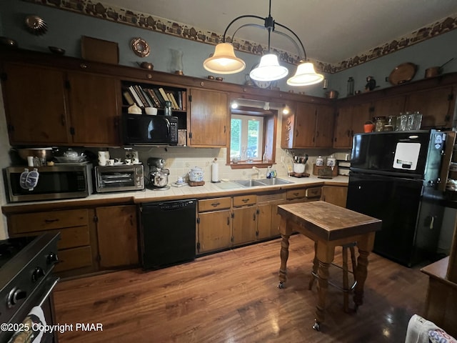 kitchen featuring a toaster, tile countertops, light wood finished floors, a sink, and black appliances