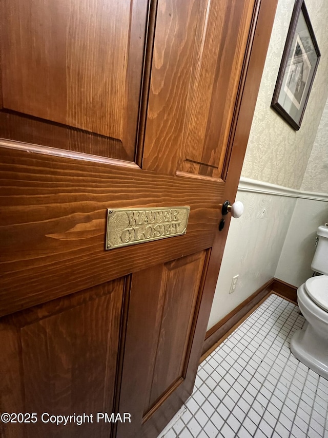 half bath featuring tile patterned flooring, baseboards, and toilet