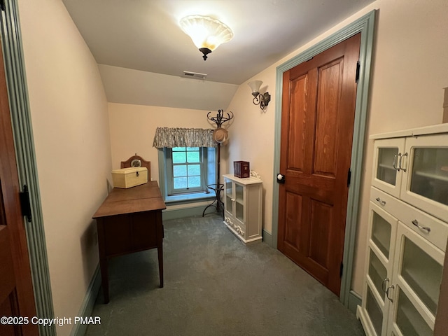 interior space with dark colored carpet, visible vents, vaulted ceiling, and baseboards