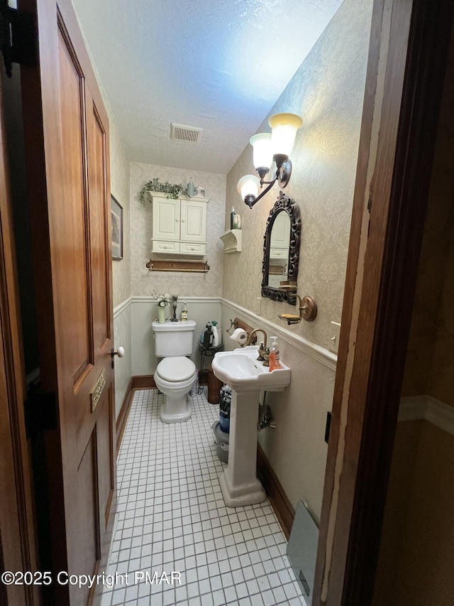 bathroom featuring toilet, tile patterned flooring, visible vents, and wallpapered walls