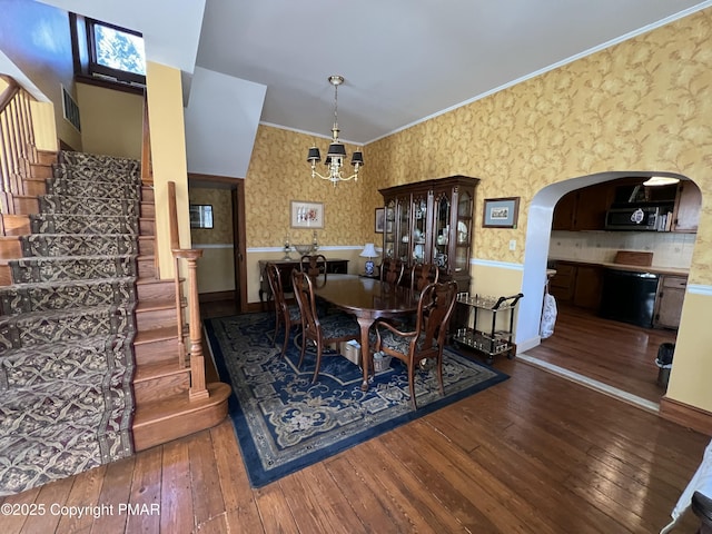 dining room with arched walkways, wood-type flooring, and wallpapered walls