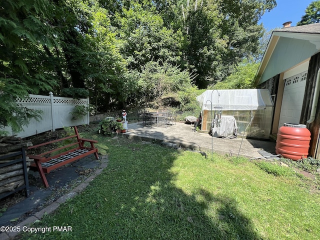 view of yard with fence, an outbuilding, a patio, and an exterior structure