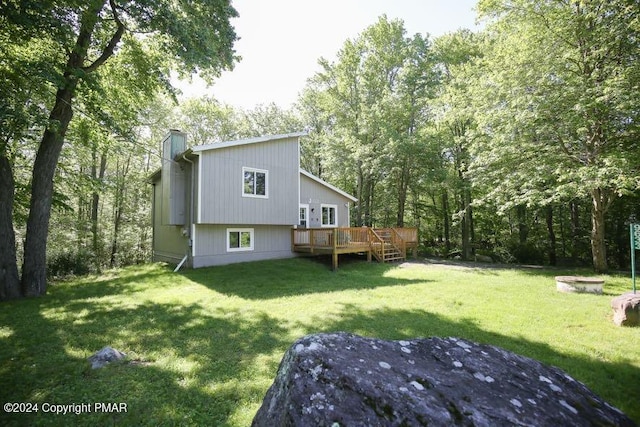 rear view of property with a chimney, a deck, and a yard