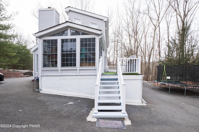 exterior space featuring a trampoline, stairway, and a chimney