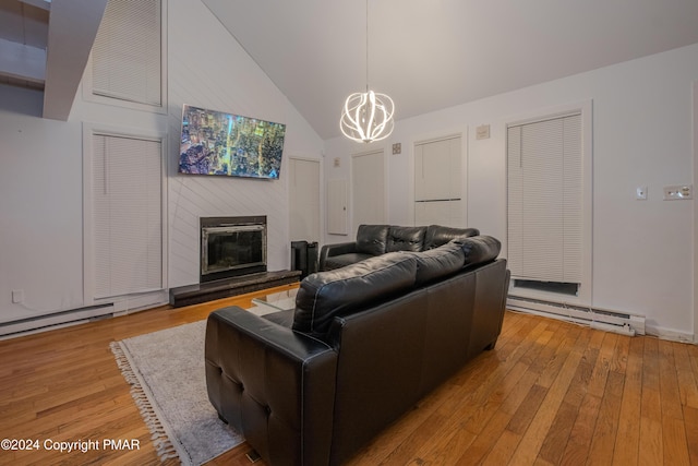 living room featuring light wood-type flooring, a baseboard heating unit, a notable chandelier, and a glass covered fireplace