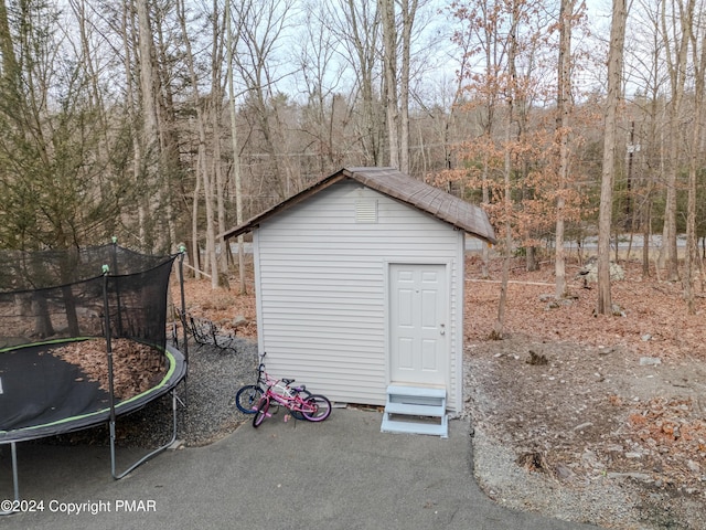 view of outbuilding with a trampoline and an outbuilding