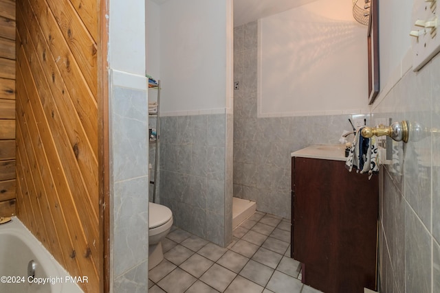 full bathroom with tile walls, toilet, vanity, tile patterned flooring, and tiled shower