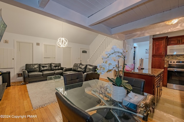 dining space with light wood-type flooring, an inviting chandelier, stairs, and lofted ceiling with beams