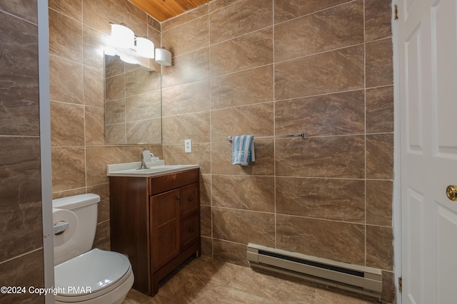 bathroom with a baseboard heating unit, tile walls, vanity, and toilet