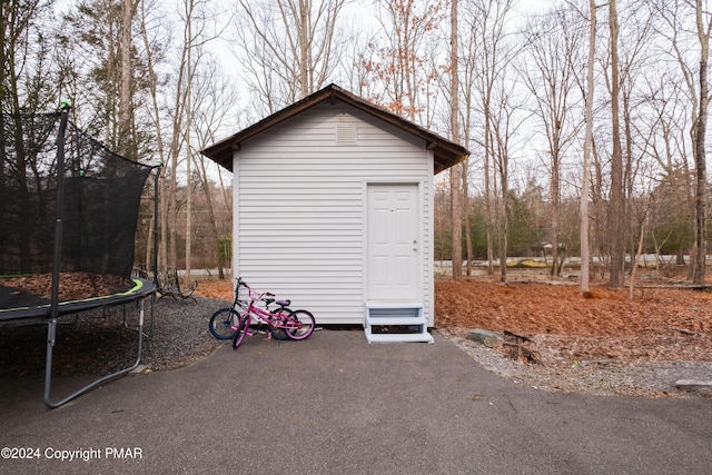 view of outbuilding with a trampoline and an outdoor structure