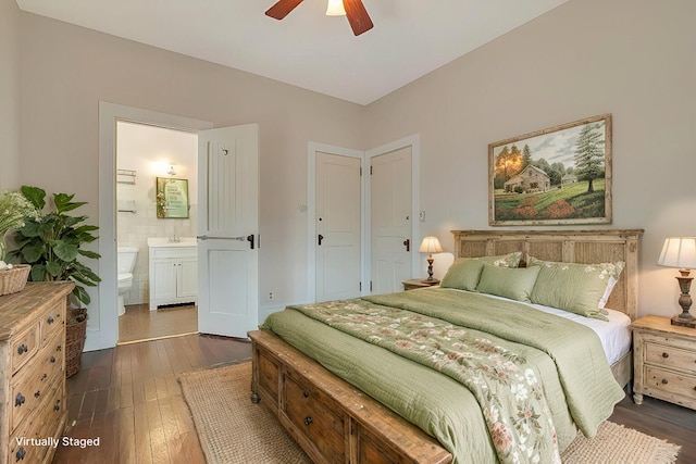bedroom with a ceiling fan, a sink, dark wood-style floors, and ensuite bath