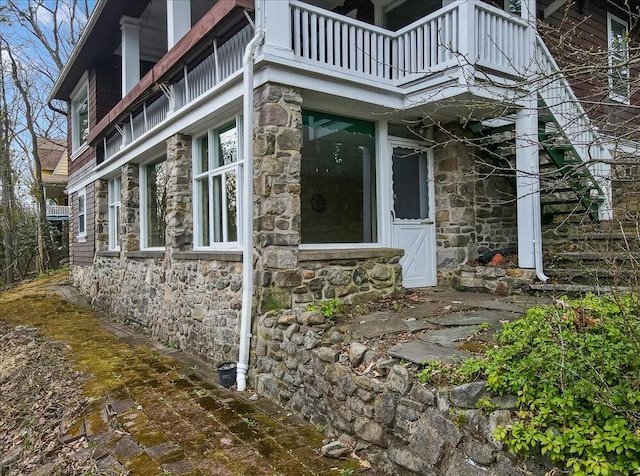 view of property exterior with stone siding and a balcony