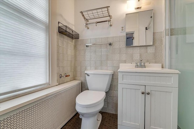 full bathroom featuring tile walls, toilet, radiator, and vanity