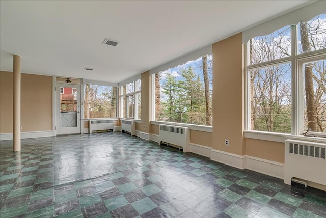 unfurnished sunroom with visible vents, radiator heating unit, and baseboards