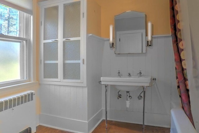 full bath with radiator heating unit, wainscoting, and a healthy amount of sunlight