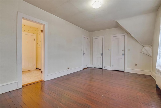 additional living space featuring baseboards and hardwood / wood-style flooring