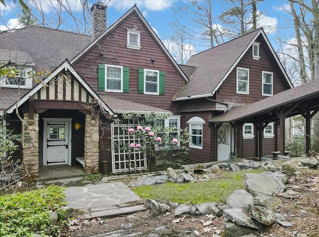 view of front facade with a chimney and a shingled roof