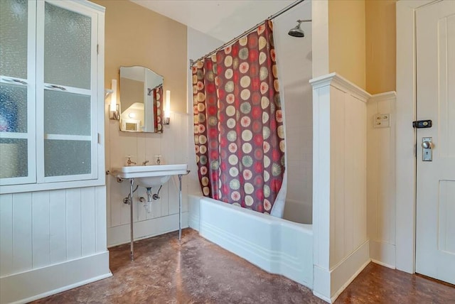 full bathroom featuring concrete floors, a wainscoted wall, and shower / bath combo with shower curtain