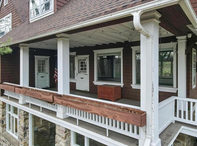 view of exterior entry with covered porch and roof with shingles