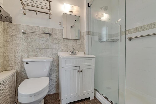 bathroom featuring toilet, vanity, tile walls, and a stall shower