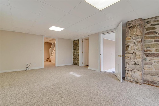 finished below grade area with a paneled ceiling, light colored carpet, baseboards, and stairway