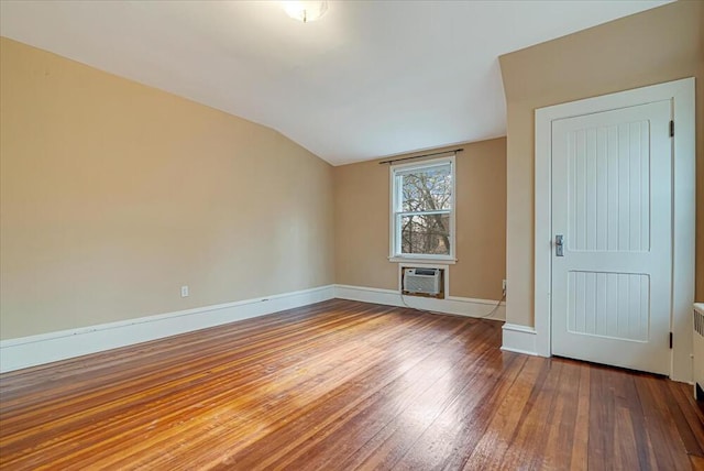 spare room with hardwood / wood-style floors, a wall mounted AC, baseboards, and lofted ceiling