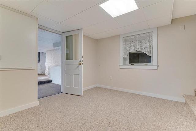 carpeted spare room featuring baseboards, a drop ceiling, and stairs