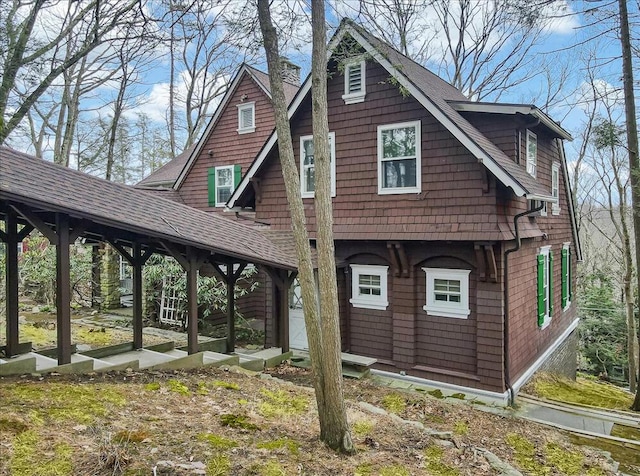 rear view of property featuring a chimney and a shingled roof
