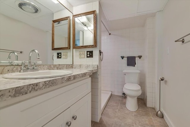 bathroom featuring visible vents, toilet, vanity, tile patterned floors, and tiled shower