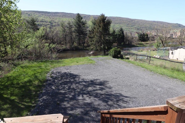 exterior space with a water view, fence, and a wooded view
