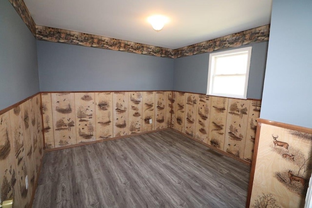 empty room with wood finished floors and a wainscoted wall