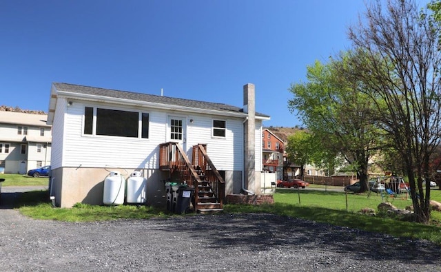 back of property with a lawn, fence, and a chimney