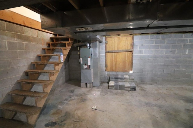 unfinished basement featuring stairs, concrete block wall, heating unit, and visible vents