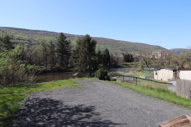 view of road featuring a water and mountain view and a view of trees