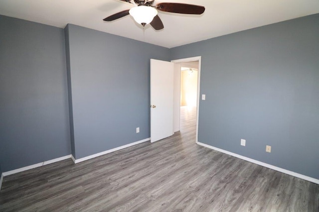 empty room with baseboards, ceiling fan, and wood finished floors