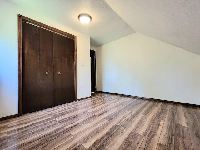 157 Seminole Trl, Tobyhanna, PA 18466 - unfurnished bedroom featuring light wood-type flooring, vaulted ceiling, a textured ceiling, baseboards, and a closet