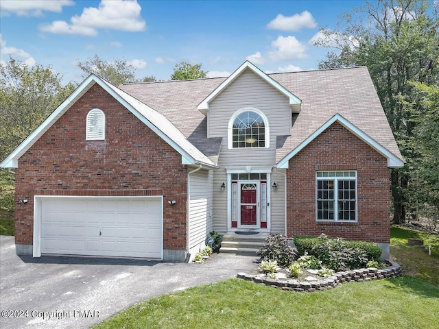 traditional-style house with a front lawn, brick siding, a garage, and driveway