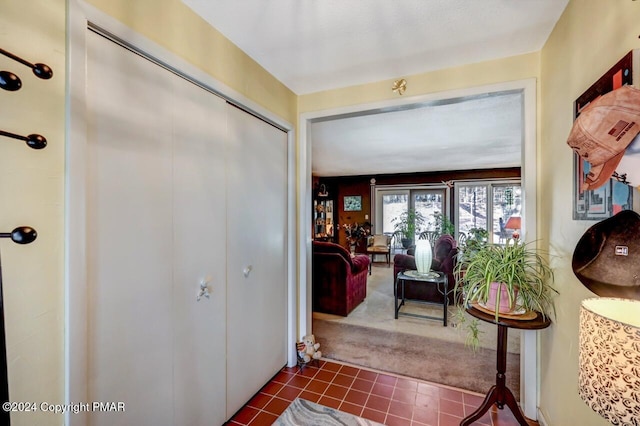 foyer featuring dark tile patterned floors and dark carpet