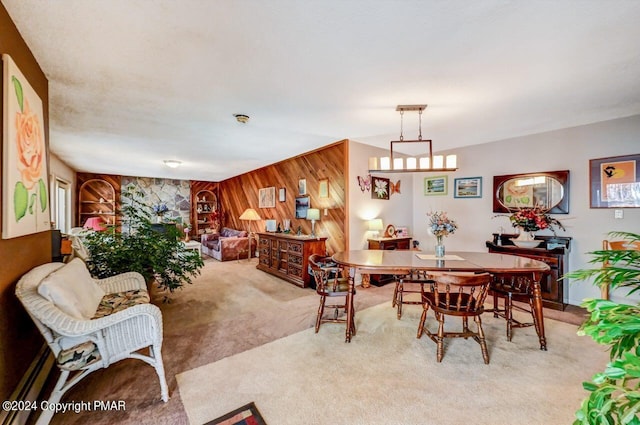 dining space featuring light carpet and wooden walls