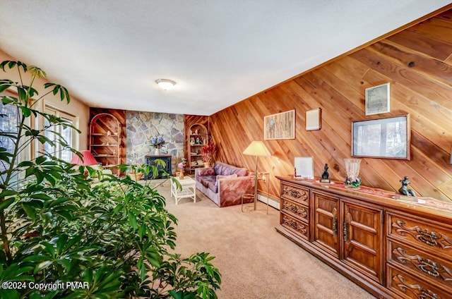 living area featuring wood walls, a baseboard heating unit, a stone fireplace, and light colored carpet