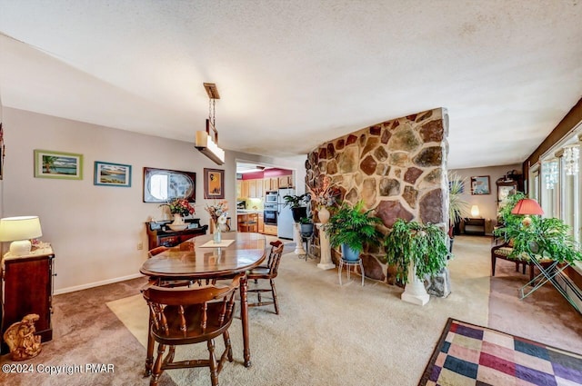 dining area featuring light carpet, a fireplace, a textured ceiling, and baseboards