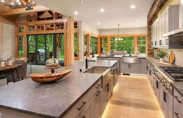 kitchen featuring an island with sink, wall chimney exhaust hood, recessed lighting, stainless steel gas cooktop, and a sink