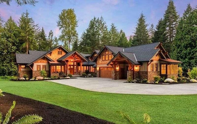 view of front of property featuring a yard, concrete driveway, a garage, and stone siding