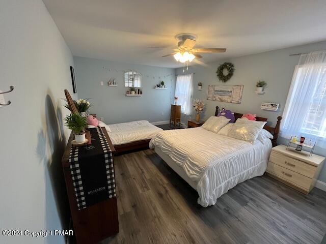 bedroom featuring multiple windows, ceiling fan, baseboards, and wood finished floors