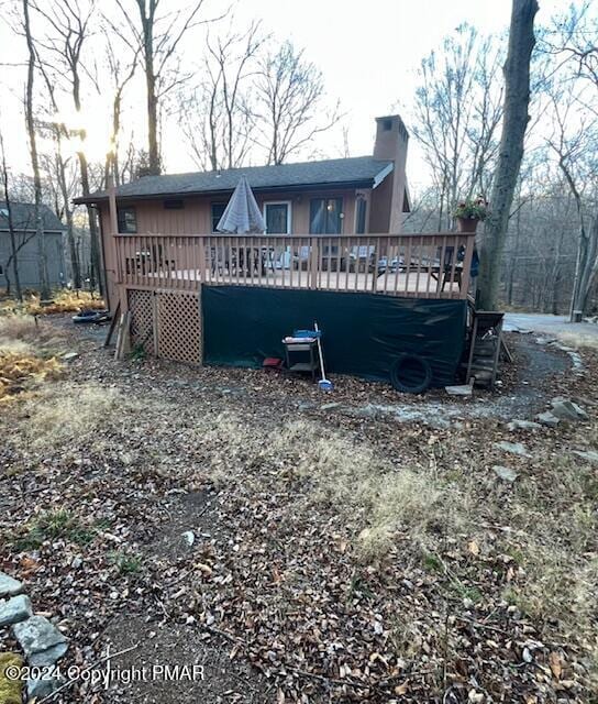 back of house featuring a chimney and a wooden deck