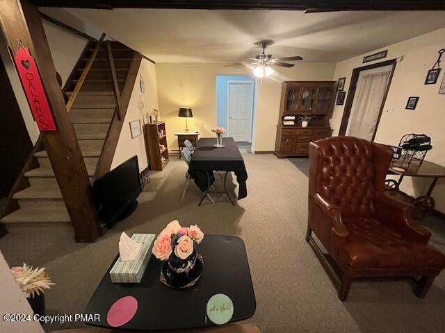 carpeted living room featuring stairs and a ceiling fan