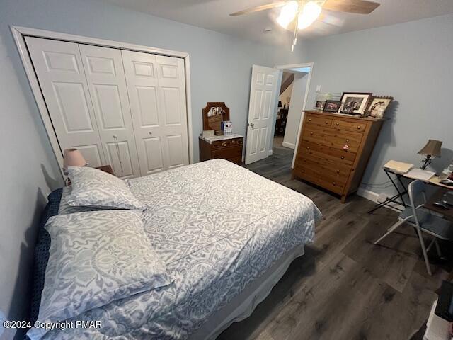 bedroom featuring a closet, dark wood finished floors, a ceiling fan, and baseboards