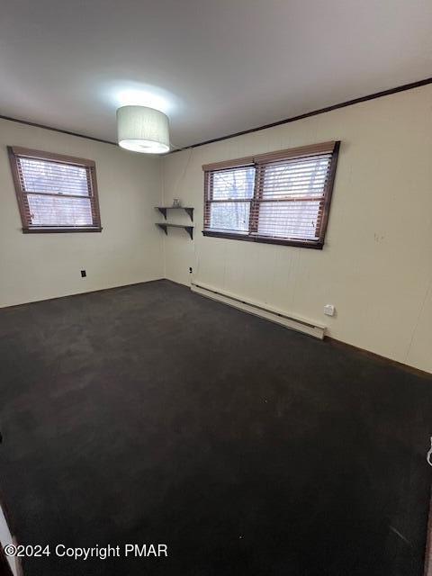 empty room with a baseboard heating unit and dark carpet