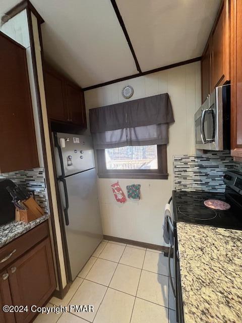 kitchen featuring stainless steel appliances, light tile patterned flooring, light stone counters, and decorative backsplash